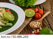 Thai style spicy food, Som Tum food concept, props decoration Garlic, lemon, peanuts, tomatoes, and shallots on wood table. Стоковое фото, агентство Ingram Publishing / Фотобанк Лори