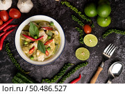 Pork green curry in a white bowl with spices on a black cement background. Стоковое фото, агентство Ingram Publishing / Фотобанк Лори