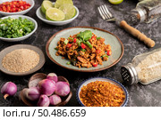 Spicy minced pork salad with chili flakes, lime, chopped green onions, chilli and roasted rice, sliced ??shallots on a cement floor. Стоковое фото, агентство Ingram Publishing / Фотобанк Лори