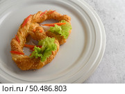 Freshly baked soft pretzel with generous sprinkling of coarse salt and sesame on white dish, decorate with lettuce and carrot beautifully, copy space. Стоковое фото, агентство Ingram Publishing / Фотобанк Лори