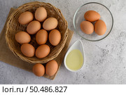 Selective focus eggs on sack cloth, many eggs on wicker basket and glasses bowl, the egg whisk placed on the floor, preparing for cooking food or dessert, copy space. Стоковое фото, агентство Ingram Publishing / Фотобанк Лори