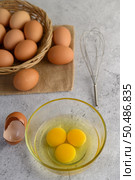 Organic eggs on sack cloth, many eggs on wicker basket and glasses bowl, oil and egg whisk placed on the floor, preparing for cooking food or dessert, copy space. Стоковое фото, агентство Ingram Publishing / Фотобанк Лори