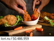 Two hand holding crispy fried chicken dipped in tomato sauce.Selective focus. Стоковое фото, агентство Ingram Publishing / Фотобанк Лори