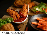 crispy fried chicken dipped in tomato sauce. Selective focus. Стоковое фото, агентство Ingram Publishing / Фотобанк Лори