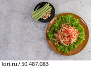 Thai papaya salad on salad in a wooden plate with Yardlong beans and garlic, Top view. Стоковое фото, агентство Ingram Publishing / Фотобанк Лори