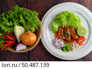 Top View Spicy salad of sardine with tomato sauce arranged nicely in white dish and ingredient herb for cooking put in a wicker basket on wooden table, copy space. Стоковое фото, агентство Ingram Publishing / Фотобанк Лори
