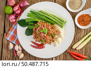 Spicy Minced Pork Salad on a white plate with red onion, lemon grass, garlic, yardlong beans, kaffir lime leaves, and spring onion. Стоковое фото, агентство Ingram Publishing / Фотобанк Лори