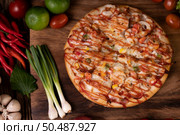 Pizza with sausage, corn, beans, shrimp and bacon on a wooden plate. Стоковое фото, агентство Ingram Publishing / Фотобанк Лори