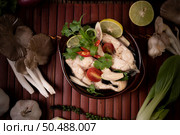 Boil the fish infusion with tomatoes, mushrooms, coriander, spring onion and lemongrass in a bowl. Стоковое фото, агентство Ingram Publishing / Фотобанк Лори