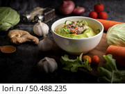Pork cabbage soup with carrots, chopped green onions, cucumber in a wooden plate on a wooden plate. Стоковое фото, агентство Ingram Publishing / Фотобанк Лори