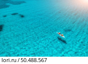 Aerial view of kayak with people in blue sea at summer sunny day. Man and woman on floating canoe in clear azure water. Sardinia island, Italy. Tropical landscape. Sup board. Active travel. Top view. Стоковое фото, агентство Ingram Publishing / Фотобанк Лори