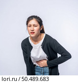 A woman standing with a stomach ache and presses her hand on her stomach. Стоковое фото, агентство Ingram Publishing / Фотобанк Лори