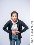 A woman standing with a stomach ache and presses her hand on her stomach. Стоковое фото, агентство Ingram Publishing / Фотобанк Лори