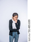 A woman coughing and covering her mouth with her hand. Стоковое фото, агентство Ingram Publishing / Фотобанк Лори