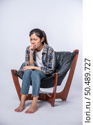 A woman sitting in a chair with abdominal pain and pressing her hand on her stomach. Стоковое фото, агентство Ingram Publishing / Фотобанк Лори