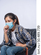 An uncomfortable woman sitting on a chair and wearing a mask. Стоковое фото, агентство Ingram Publishing / Фотобанк Лори