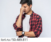 A man with a migraine headache holding her hand in her nose. Стоковое фото, агентство Ingram Publishing / Фотобанк Лори