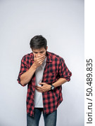 A man standing with a stomachache Put your hands on your stomach and cover your mouth. Стоковое фото, агентство Ingram Publishing / Фотобанк Лори