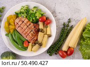Chicken steak topped with white sesame, peas, tomatoes, broccoli and pumpkin in a white plate. Стоковое фото, агентство Ingram Publishing / Фотобанк Лори
