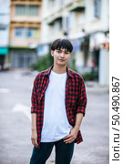 A young man in a striped shirt is standing on the street. Стоковое фото, агентство Ingram Publishing / Фотобанк Лори