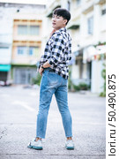A young man in a striped shirt is standing on the street. Стоковое фото, агентство Ingram Publishing / Фотобанк Лори