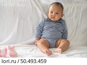 A baby learns to sit on a white bed. Стоковое фото, агентство Ingram Publishing / Фотобанк Лори