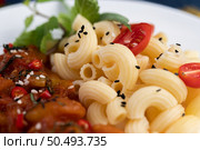 Stir-fried macaroni with tomato, chili, pepper seeds and basil in a white dish. Стоковое фото, агентство Ingram Publishing / Фотобанк Лори