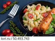 Stir-fried macaroni and sausage in a pan with tomatoes Fresh pepper seeds and a fork on the cement ground. Стоковое фото, агентство Ingram Publishing / Фотобанк Лори