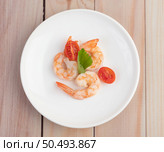 Three fresh shrimp and half tomatoes in a white plate on a wooden. Стоковое фото, агентство Ingram Publishing / Фотобанк Лори