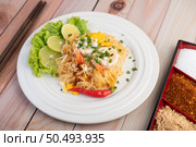 Fresh Pad Thai Shrimp with lime, lettuce, omelet and spring onions in a white plate on wooden. Стоковое фото, агентство Ingram Publishing / Фотобанк Лори