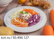 Tuna salad with carrots, tomatoes, cabbage on a white plate on a wooden floor. Стоковое фото, агентство Ingram Publishing / Фотобанк Лори