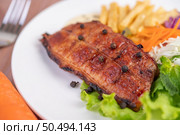 Fish steak with french fries, kiwi, lettuce, carrots, tomatoes, and cabbage in a white dish. Стоковое фото, агентство Ingram Publishing / Фотобанк Лори