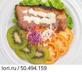 Fish steak with french fries, kiwi, lettuce, carrots, tomatoes, and cabbage in a white dish. Стоковое фото, агентство Ingram Publishing / Фотобанк Лори