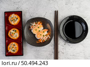 Sushi is in a plate with chopsticks and dipping sauce on a white cement floor. Стоковое фото, агентство Ingram Publishing / Фотобанк Лори