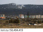 Заброшенный огород на пустыре на окраине города. Развалины сараев, парников и заборов. Неблагоустроенная территория в окрестностях северного города. Вдали видны городские кварталы, многоэтажные дома, церковь и горы. Проблемы благоустройства и развития территорий в Сибири и на Дальнем Востоке России. Город Магадан, Магаданская область, Россия. Редакционное фото, фотограф Андрей Степанов / Фотобанк Лори