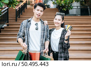 Smiley Young couple holding multiple paper shopping bag going down stairs of large shopping mall and pretty woman show credit card in hand,  Lifestyle and shopping concept, copy space. Стоковое фото, агентство Ingram Publishing / Фотобанк Лори