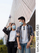 Asian Young Couple in protection mask standing outdoor of large building, They are discussion with happiness, New normal lifestyle amid coronavirus outbreak. Стоковое фото, агентство Ingram Publishing / Фотобанк Лори