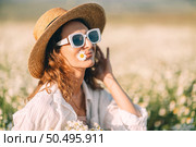 Daisy flower Woman Field. Sunny daytime: Woman enjoys daisies, wearing hat and shades in meadow for summer joy. Стоковое фото, фотограф svetograph / Фотобанк Лори