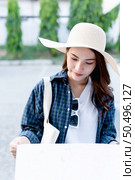Portrait smiley young backpacker female in sombrero checking location on paper map in hand. Стоковое фото, агентство Ingram Publishing / Фотобанк Лори