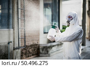 Disinfection specialist man in personal protective equipment (ppe) suit, gloves, mask and face shield, cleaning Quarantine area with a bottle of pressurized spray disinfectant to remove coronavirus. Стоковое фото, агентство Ingram Publishing / Фотобанк Лори