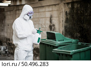 Disinfection specialist man in personal protective equipment (ppe) suit, gloves, mask and face shield, cleaning Quarantine area with a bottle of pressurized spray disinfectant to remove coronavirus. Стоковое фото, агентство Ingram Publishing / Фотобанк Лори