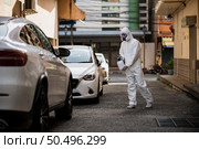 Disinfection specialist man in personal protective equipment (ppe) suit, gloves, mask and face shield, cleaning Quarantine area with a bottle of pressurized spray disinfectant to remove coronavirus. Стоковое фото, агентство Ingram Publishing / Фотобанк Лори