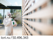 Disinfection specialist staff in personal protective equipment (ppe) suit, gloves, mask and face shield, cleaning Quarantine area with a bottle of pressurized spray disinfectant to remove covid-19. Стоковое фото, агентство Ingram Publishing / Фотобанк Лори