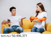 Asian young couple quarrels while cleaning in the living room, Young woman wearing gloves and holding spray bottle in hand with feel dissatisfied her husband, family issues and relationship concept. Стоковое фото, агентство Ingram Publishing / Фотобанк Лори