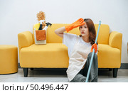 Young housekeeper woman sitting near sofa in living room with feel tired, She wipe sweat and take a break after finishing cleaning the house, copy space. Стоковое фото, агентство Ingram Publishing / Фотобанк Лори