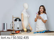 Portrait of young pretty female fashion designer stylish smile during working at fashion studio, Tailor woman’s taking measurements with measuring tape on mannequin in studio at home. Стоковое фото, агентство Ingram Publishing / Фотобанк Лори