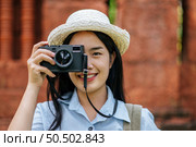 Portrait young backpacker female wearing hat traveling in ancient site, She smiling and use camera taking photo with happiness, copy space. Стоковое фото, агентство Ingram Publishing / Фотобанк Лори