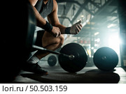 Below view of unrecognizable bodybuilder preparing for deadlift in a gym. Стоковое фото, агентство Ingram Publishing / Фотобанк Лори