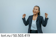 Portrait of Asian woman keeps hands clenched in fists with positiveness as achieved success in career, smiling widely, showing strong powerful, isolated over background with copy space. Стоковое фото, агентство Ingram Publishing / Фотобанк Лори