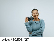 Portrait of Asian woman wearing casual clothes with a big smile on face,  holding a camera taking a picture. Isolated background in studio with blank space. Стоковое фото, агентство Ingram Publishing / Фотобанк Лори